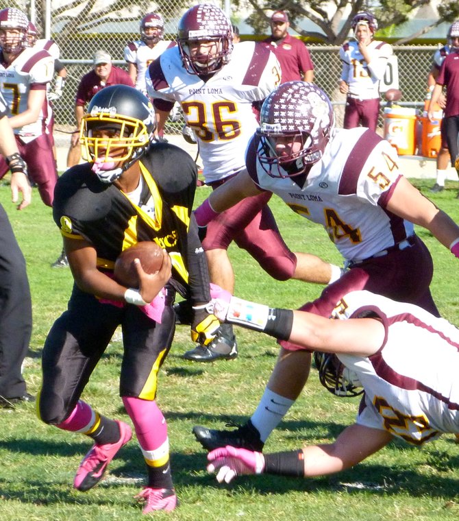 Mission Bay sophomore quarterback Devon Johnson runs forward with Point Loma junior defensive end Jake Wambaugh tugging at his jersey