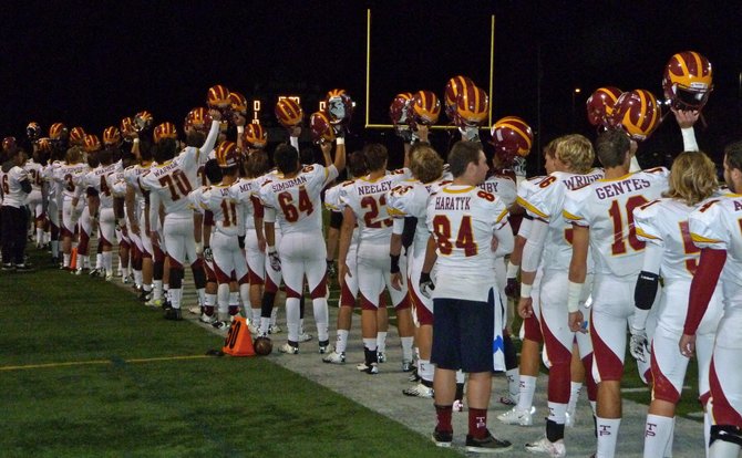 Torrey Pines players hold their helmets up at the end of the national anthem