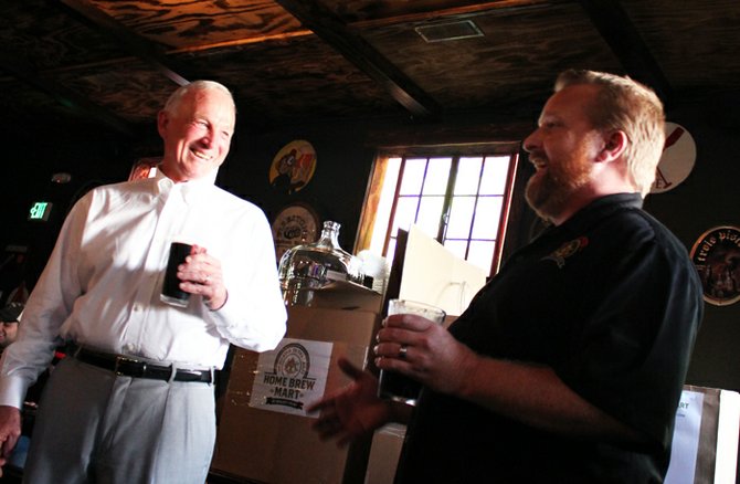 Ballast Point specialty brewer and former president of the San Diego Brewers Guild, Colby Chandler presents Sanders with a kit from Home Brew Mart