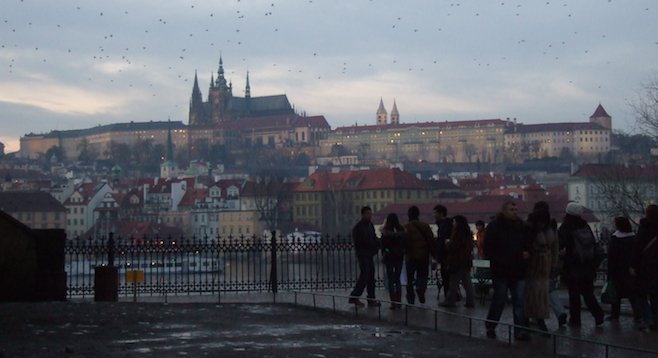 Approaching the Charles Bridge at dusk, the author's greeted by the 9th-century Prague Castle rising above the river. 