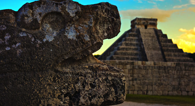 Kukulkan Pyramid (“El Castillo”) with a stone serpent in the foreground.