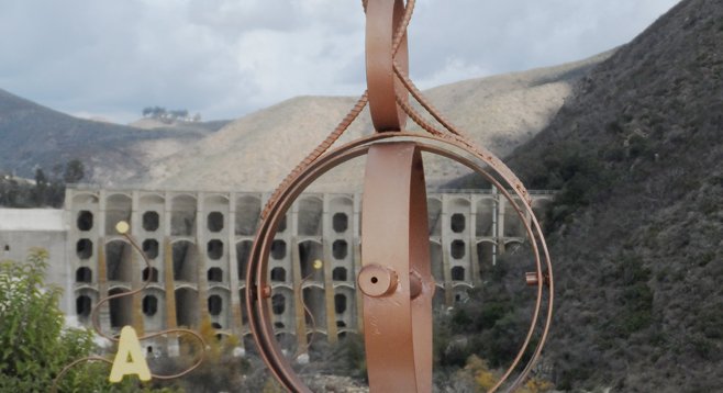 Through this pipe scope atop a rattlesnake-shaped rock wall, one can pinpoint features of Lake Hodges Dam.