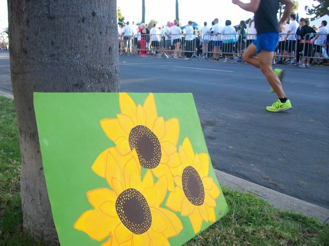 Runner at Finish Chelsea's Race in Balboa Park johs past sunflower artwork.