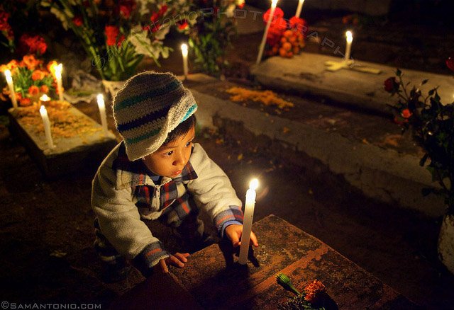 Little boy placing a candle on his deceased relative’s grave at the Xoxocotlan Cemetery
