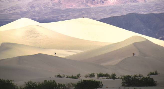 Hikers ascending Death Valley's massive sand dunes take in the wonder.  