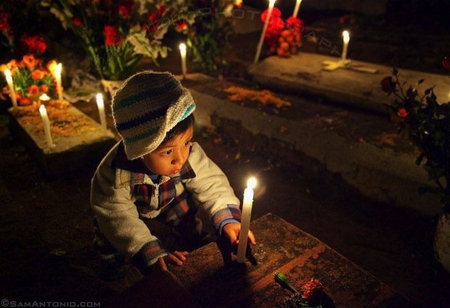 Little boy placing a candle on his deceased relative’s grave at the Xoxocotlan Cemetery.