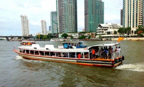 A ferry overcrowded with tourists and locals cruising along the Chao Phraya River.