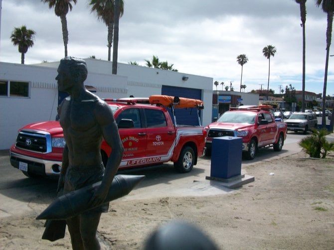 OB Lifeguard statue near Lifeguard vehicles.