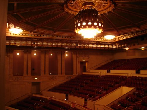 As described in 1929, "Hanging from the large gold dome of the auditorium is a huge electric fixture, studded with small lamps to imitate pearls, behind which are a number of small reflectors which throw a variation of colored lights on the ceiling of the dome." Credit www.akustiks.com.

