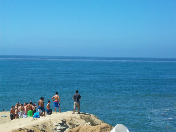 Brave souls waiting to jump off Sunset Cliffs "The Arch" in Ocean Beach.