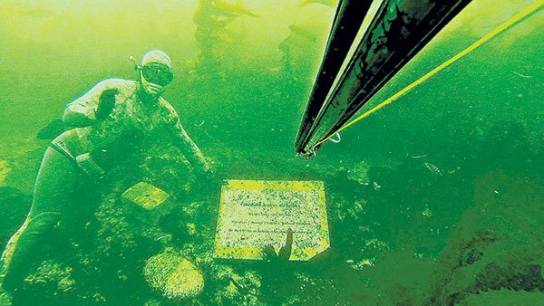 Volker Hoehne cleans off one of the markers at Tombstones, an unofffical underwater memorial park off the coast of La Jolla.