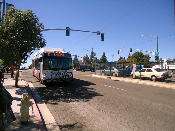 A Metropolitan Transit System C40LFR pulls up to the eastbound bus stop for route 27, across a couple streets from Clairemont High School.