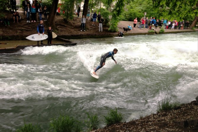 A crowd watches river surfers in Münich.