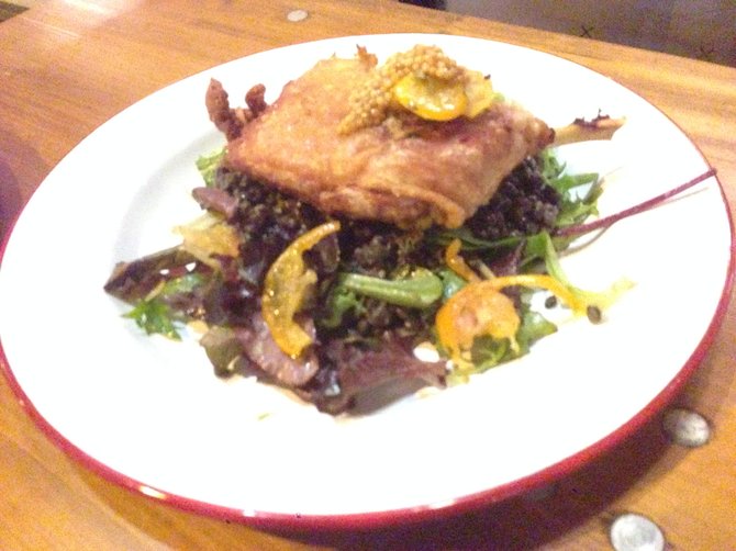 Crispy duck on a bed of lentils and greens, topped by pickled mustard seeds.