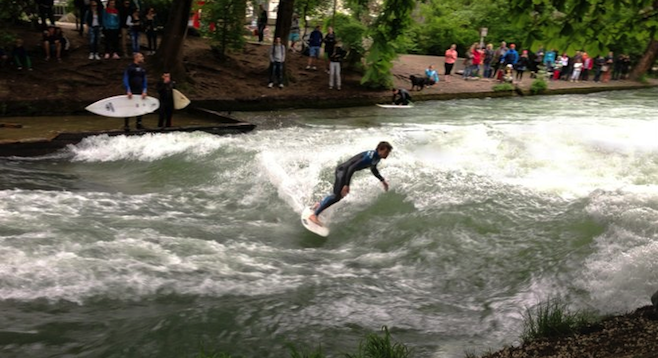 A crowd watches river surfers in Münich.