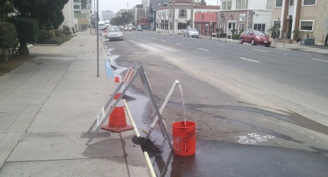 Water fills a bucket on Fifth Avenue — presumably for testing