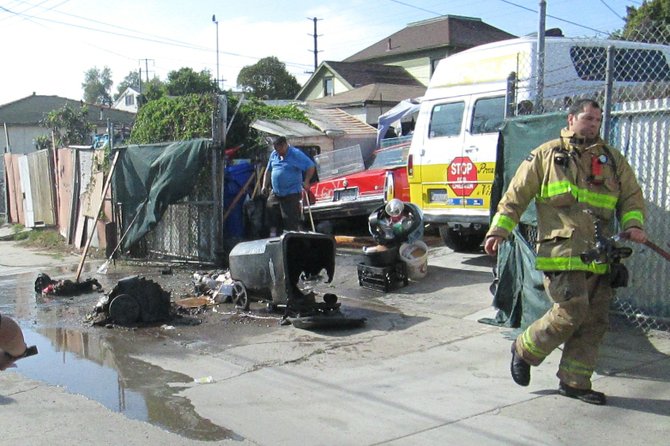 The two black trash cans involved in the fire had been sitting in the corner just inside the fence, left side of the picture, next to the blue recycling bin.  The two bird cages mentioned in the story are on top of the vehicle.