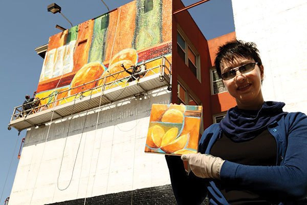 Pam Anderson, owner/founder of the now-defunct ArchitectureArt, holding a study of the Market Street mural.