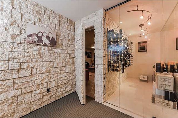 Next to the glass-walled wine room, a hidden door leads to the private gym and “man cave.”