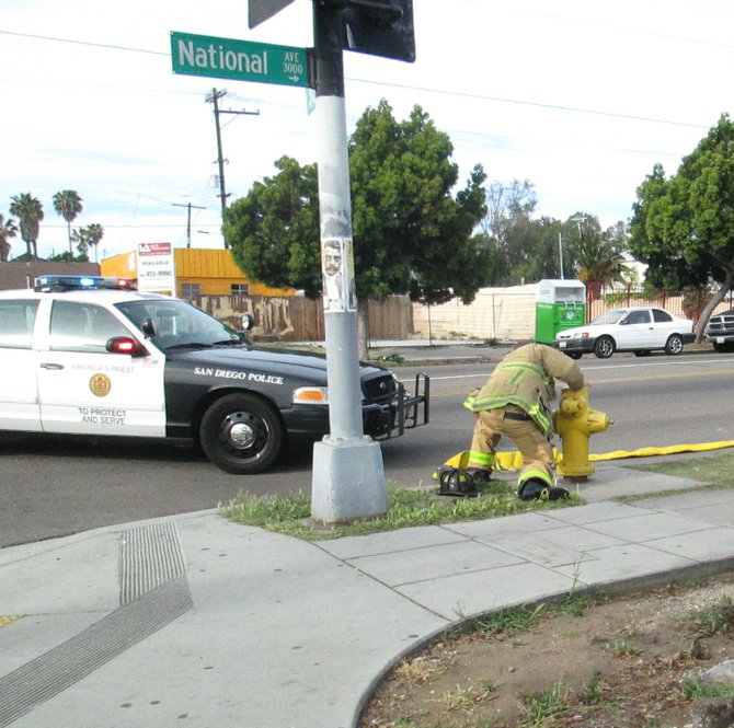 Firefighter attaching hose to hydrant at the corner of 30th and National Avenue.