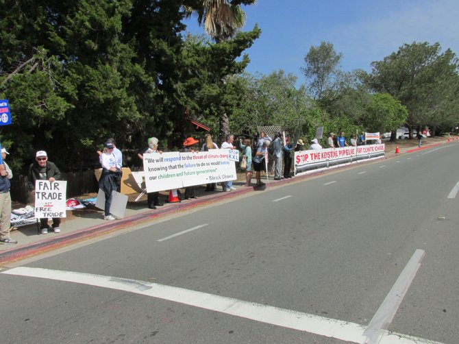 Protestors line the northwest corner of Torrey PInes Road at Dunaway Drive, two hours before the president's La Jolla visit.  