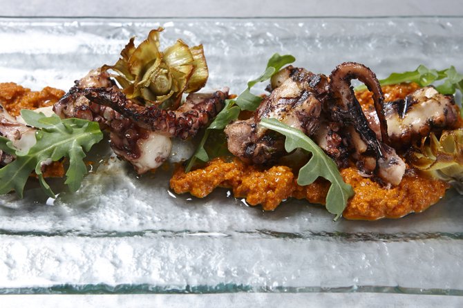 Fish Public in Kensington cooks octopus in cooking it in a bouillon of chilis, garlic, herbs and citrus, and tomato for a really long time. Then it is grilled, and served with a romesco sauce, fried shallots and garlic, lemon and arugula.
