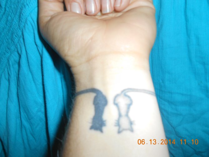 My name is Rachel Tress-Harris and I am 31 year old pharmacy technician from Oceanside, Ca. This tattoo is of 2 cats black & white representing ying and yang with their tails wrapping around my wrist (like a bracelet) intertwining into a heart on the top of my wrist. This tattoo represents me and my husband and also ying and yang. A constant reminder of the good and the bad in everything.