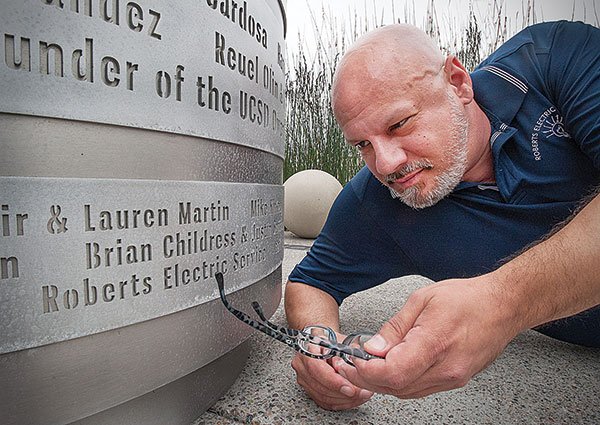 Mat Wahlstrom points to his business’s name on the base of the Pride flag monument.