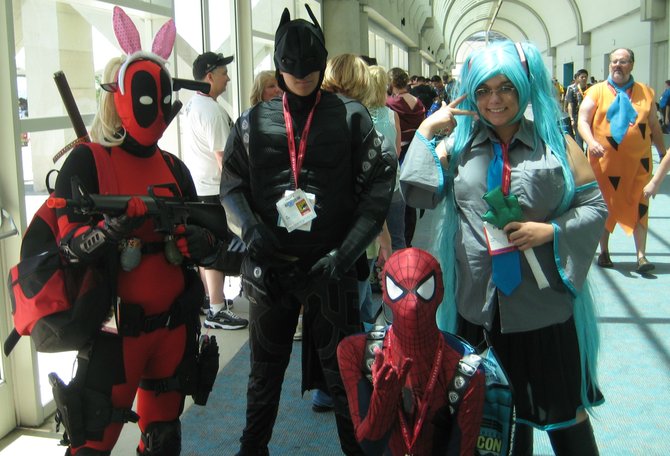 Deadpool, Night Owl character from Watchmen, Spider-Man, costumed woman and Fred Flintstone walking by the group of 4