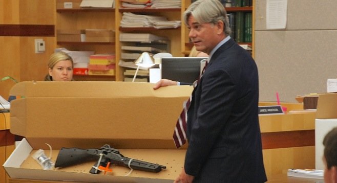 Prosecutor David Bost shows a gun to the jury during first trial. Photo by Eva