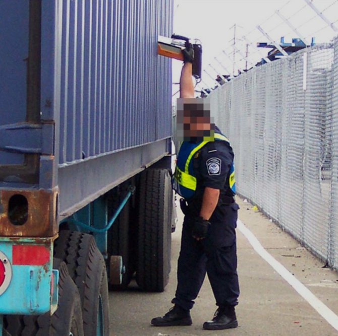 CBP agent checking shipping container with radio isotope identification device