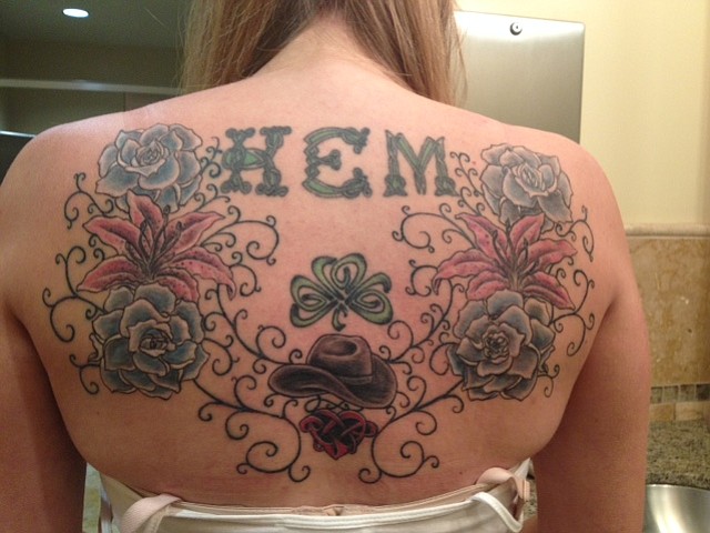 Hi there, my name is Laurie Metzger and I live in San Marcos and am 30 yrs old.  I work for a marketing firm as a Client services representative. 

I originally had the Initials and shamrock in honor of my late mother.  I wanted to incorporate myself and my father into it.  I got the rest added on.  Lilies being my favorite flower and gardenias my moms.  I did not want white tatted on me for the gardenias so I made them blue for her birth stone.  I also added the stetson hat for my father, as he always wears his stetson.  Then a celtic heart to bring us all together.
