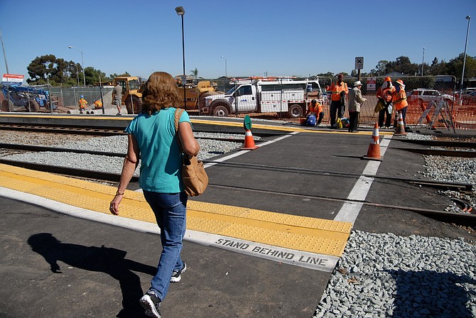 Commuter crossing the tracks at the Palm Avenue Trolley Station - November 08, 2014.