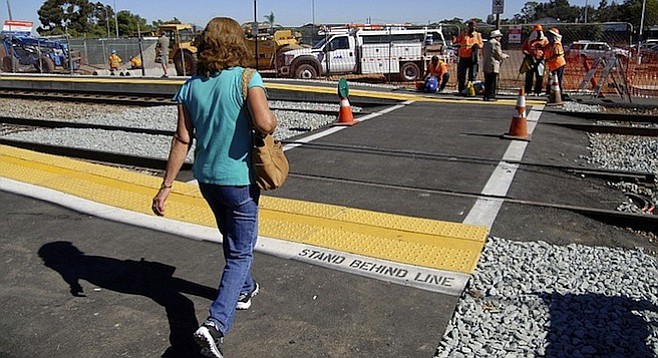 Commuter crossing the tracks at the Palm Avenue trolley station on November 8