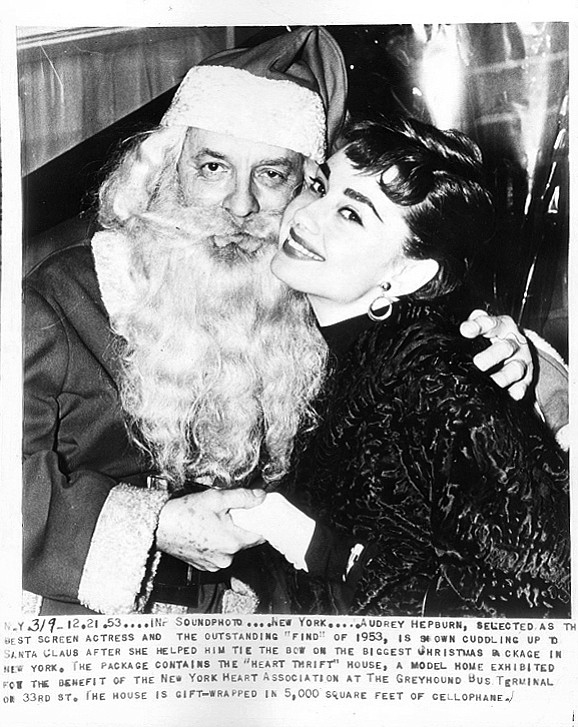 Wire photo of Audrey Hepburn hanging out with Santa at a Greyhound Bus Terminal. December 21, 1953.