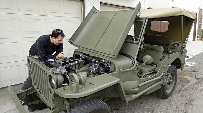 North Park resident Christopher Blauw checks the engine on his newly restored 1944 U.S. Army Jeep, built by Willys. He put it back together carefully from a big pile of parts, plus there were more pieces of the puzzle he had to buy. North Park and other neighborhood residents smile when they see this classic Jeep driving by.
