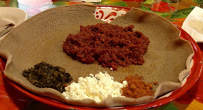 Kitfo — steak tartare, Ethiopian-style —with its flavorings on top of the injera