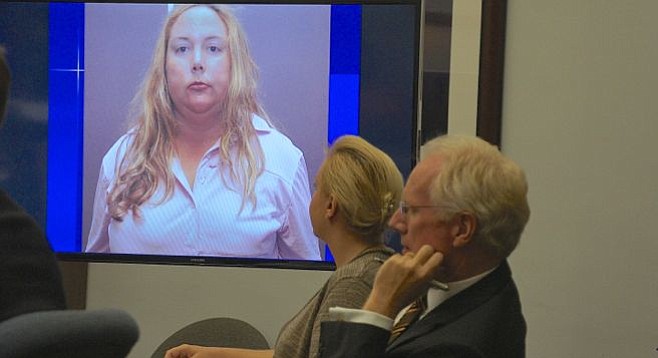 Julie Harper w attorney Paul Pfingst, she looks at a photo of herself when arrested.