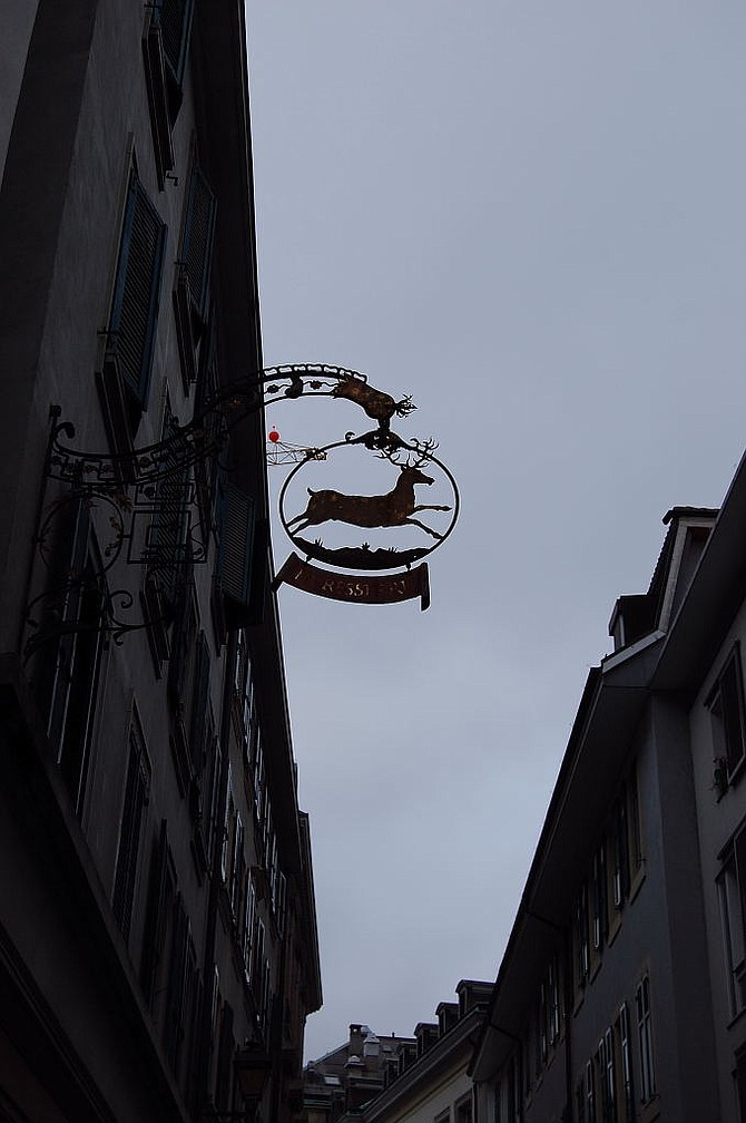 This overhead sign depicting a deer is a traditional form of Swiss advertising hundreds of years old - here, it marks where “LA RESSERRE” (“The Shed”) is located.