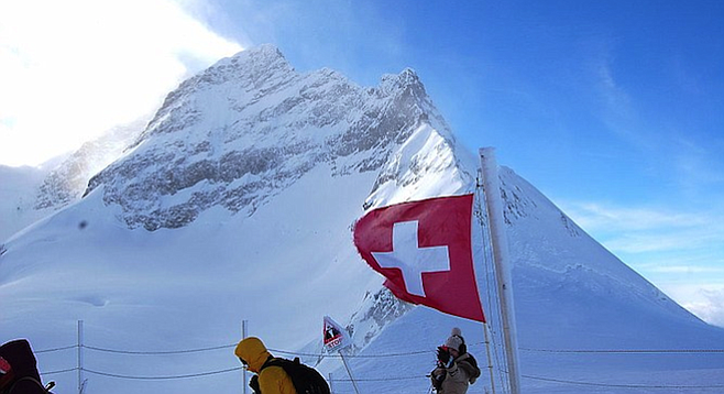 The wind-whipped Swiss flag, and tourists, at the Jungfrau's Plateau vantage point.