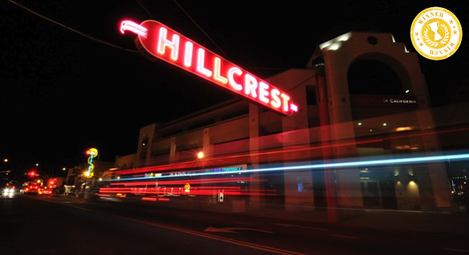 The iconic Hillcrest sign glows above University Ave. traffic at night.  (Reader stock)