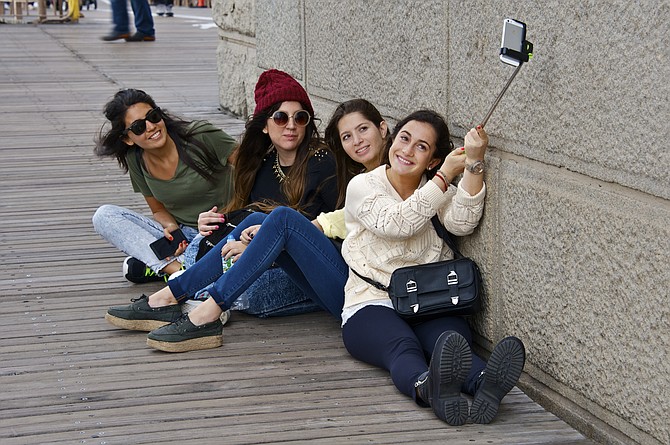 The ubiquitous selfie stick being put to use at Brooklyn Bridge.