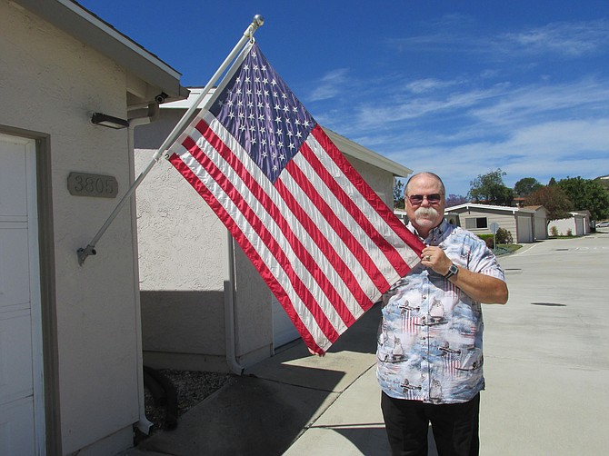 Oceanside's Michael Rank shows off his replacement flag. The security camera mounted above the flagpole helped police find the vandals.