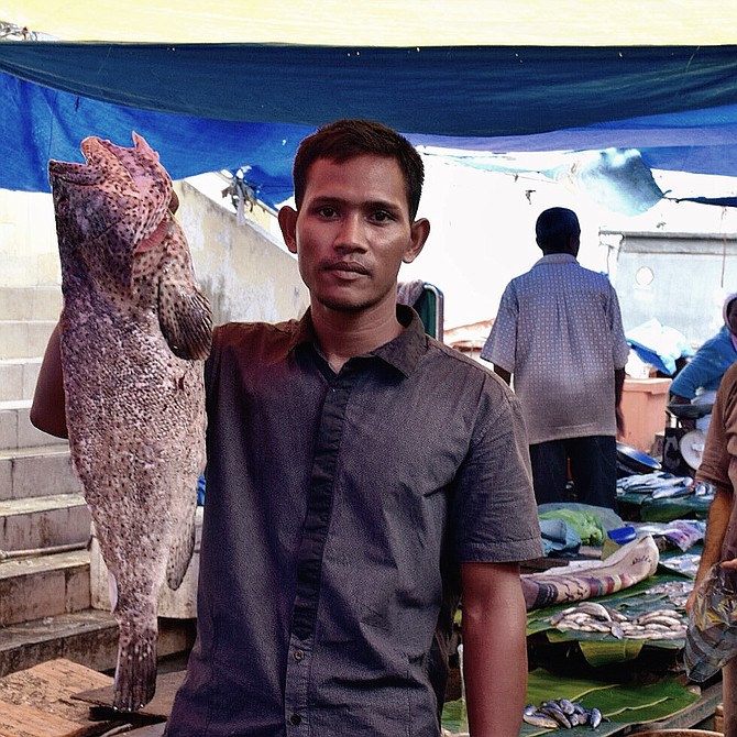 A fisherman from the local market in Sumatra, Indonesia. I was walking through the market with my camera and he stopped me and ask to take a picture of the daily catch. It was quite impressive. 