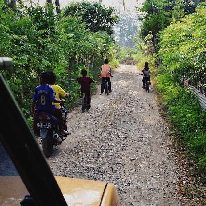 The traditional way of playing. Kids go fishing and biking through the town of Banda Aceh, Indonesia.