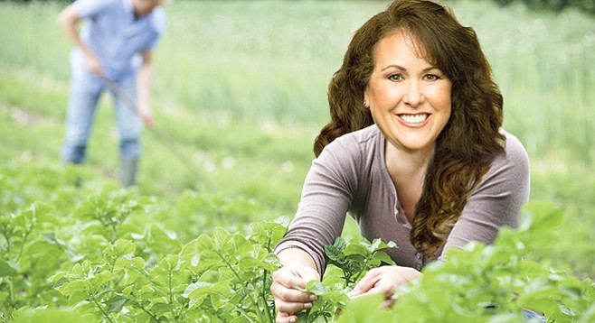 Lorena Gonzalez, depicted as happy in a field of greens (is any politician not?)