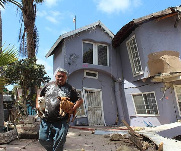 Man leaves home damaged by landslide with his two most prized possessions. (Photo: El Sol de Tijuana)