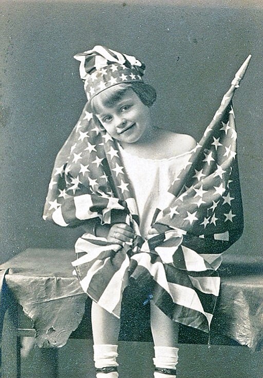 OLD GLORY IN A COUNTRY UNIITED  ---  My paternal grandmother Elizabeth Long was San Diego's Flag Girl in 1921 for a Daughters of the Revolution event. San Diego had recently decided to preserve Balboa Park after the 1915 Panama Exhibition. In January 1921, a San Diego Union Tribune editorial started the ball rolling by arguing: "Aside from all artistic or merely sentimental considerations, San Diego cannot afford to let this beautiful picture fade. Balboa Park is not a luxury to be maintained merely for the pleasure of San Diego; it is a necessary of our civic life and a profitable adjunct of our future metropolitan development. To keep this wonderful possession and to make the most of its limitless resources of beauty and pleasure is the main object of those who have organized the Mid-Winter exposition movement. Its purpose should appeal to every San Diegan, every public-spirited citizen and every lover of the beautiful in art and nature." Everyone was also in a very patriotic mood in 1921 what with WWI recently ending, the first American President being inaugurated that women had voted into office, and the first Miss America was crowned. Sure, prohibition was also in full swing, but according to my grandmother, that didn't get anybody's spirits down as everyone knew a bootlegger or two. (Photo: San Diego Flag Girl Elizabeth Long Stalmer, 1921)
