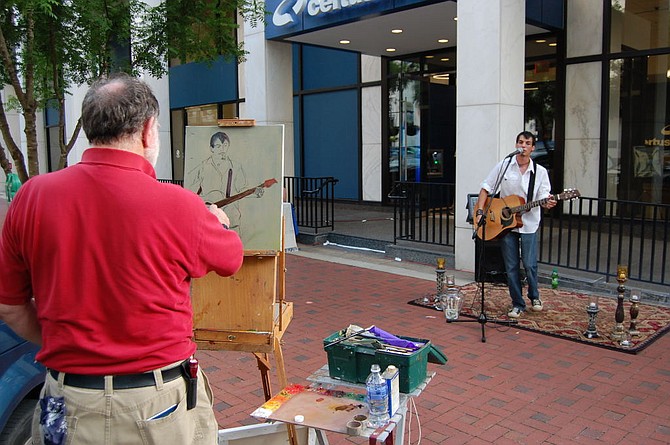 2 artists paint a troubadour during First Thursdays on Main. 