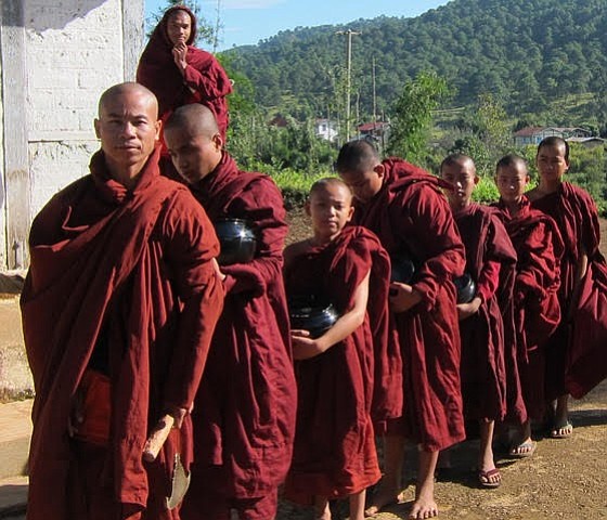 Monks beg for food with rice bowls in the Myanmar countryside.